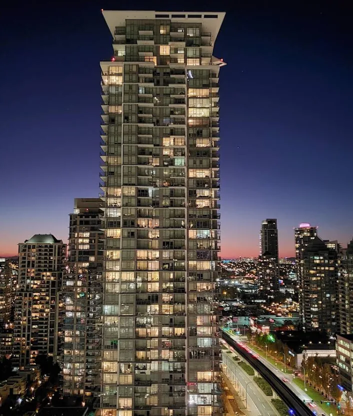 Solo District — illuminated high-rise residential tower at dusk in Burnaby with full curtain wall facade